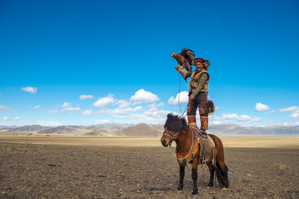 Alpamys Dalaikhan, a burkitshi (eagle hunter) demonstrates his dexterity, deftly standing atop his horse while his golden eagle balances on his arm in Bayan-Ölgii Province in western Mongolia on September 29, 2017.  Alpamys was in Bayan-Ölgii for the Golden Eagle Festival, an annual gathering and celebration of the burkitshi.  Alpamys posed for this portrait at the request of the photographer.