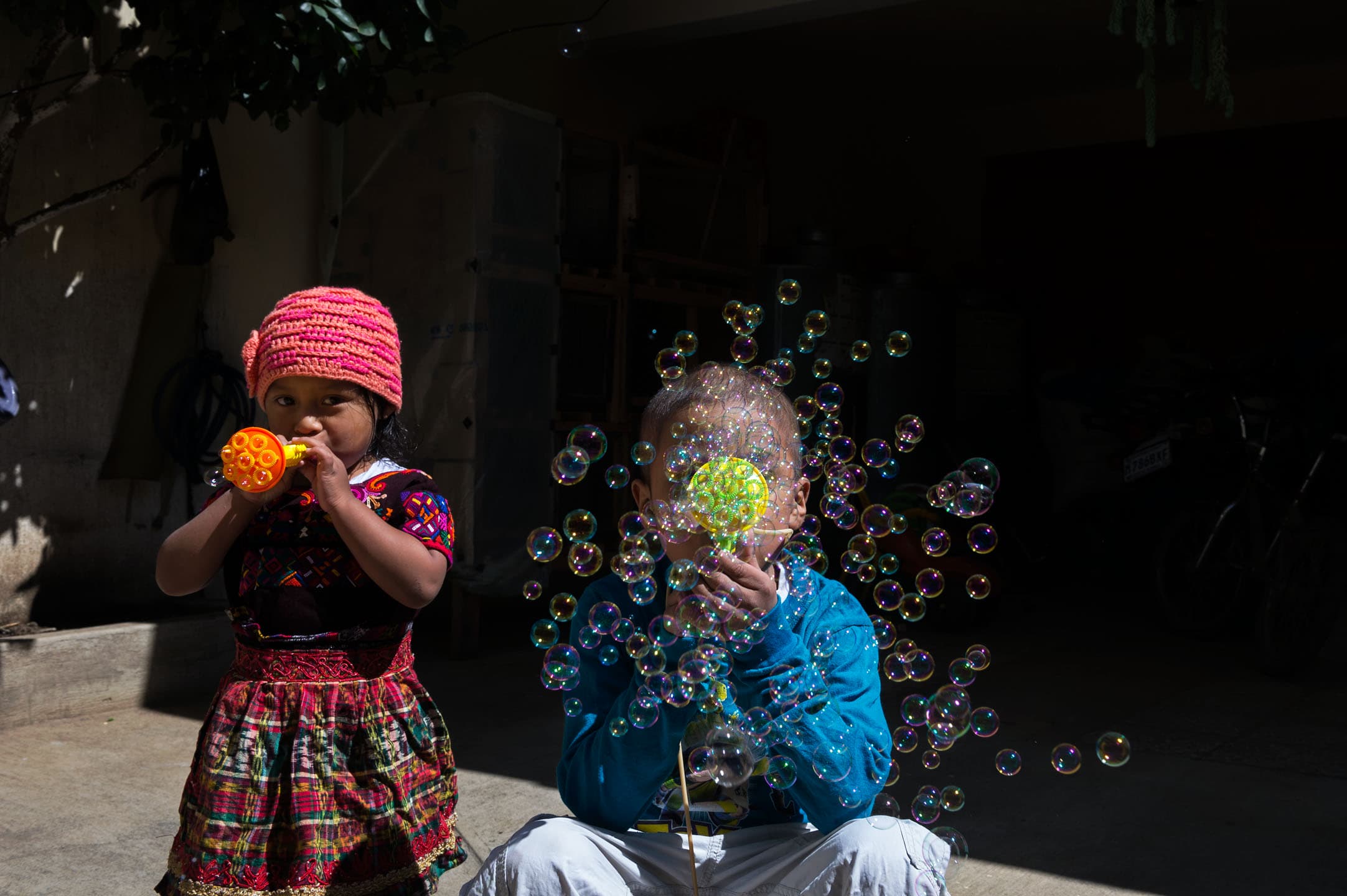 Heber and his younger sister Saraí Menchu Tamayac (age 3) make bubbles in the courtyard at his family’s home.